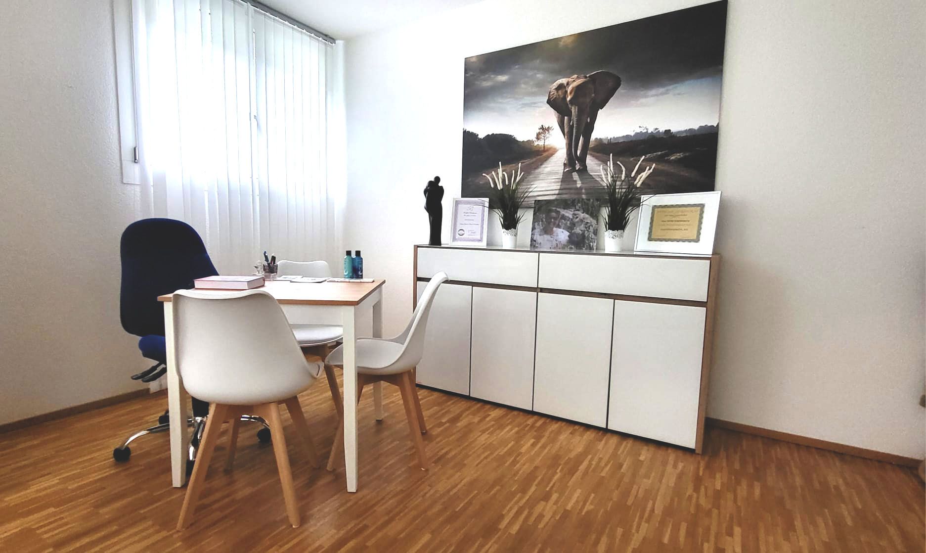 Ein Raum mit einem Tisch und Stühlen und einem Gemälde an der Wand