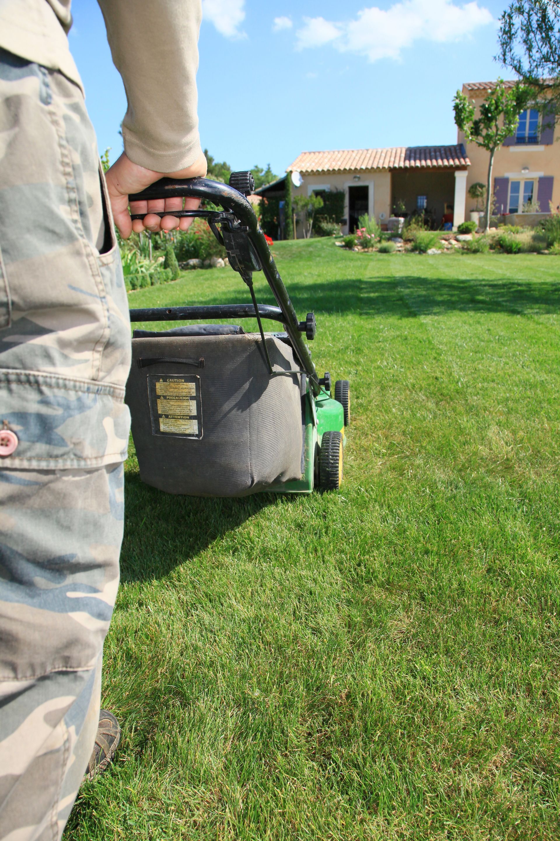 Un homme passant la tondeuse dans un jardin
