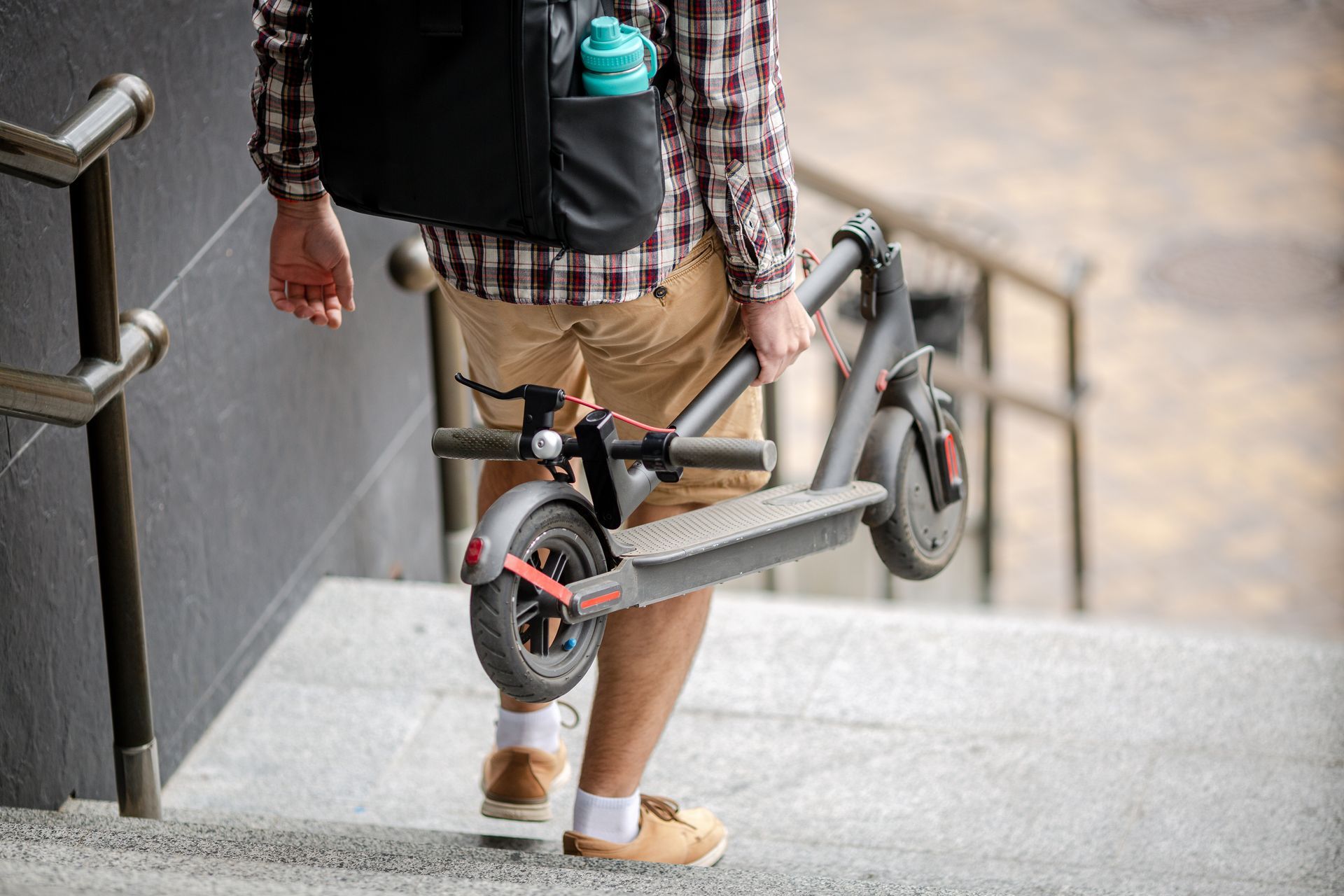 Un homme portant une trottinette pliée