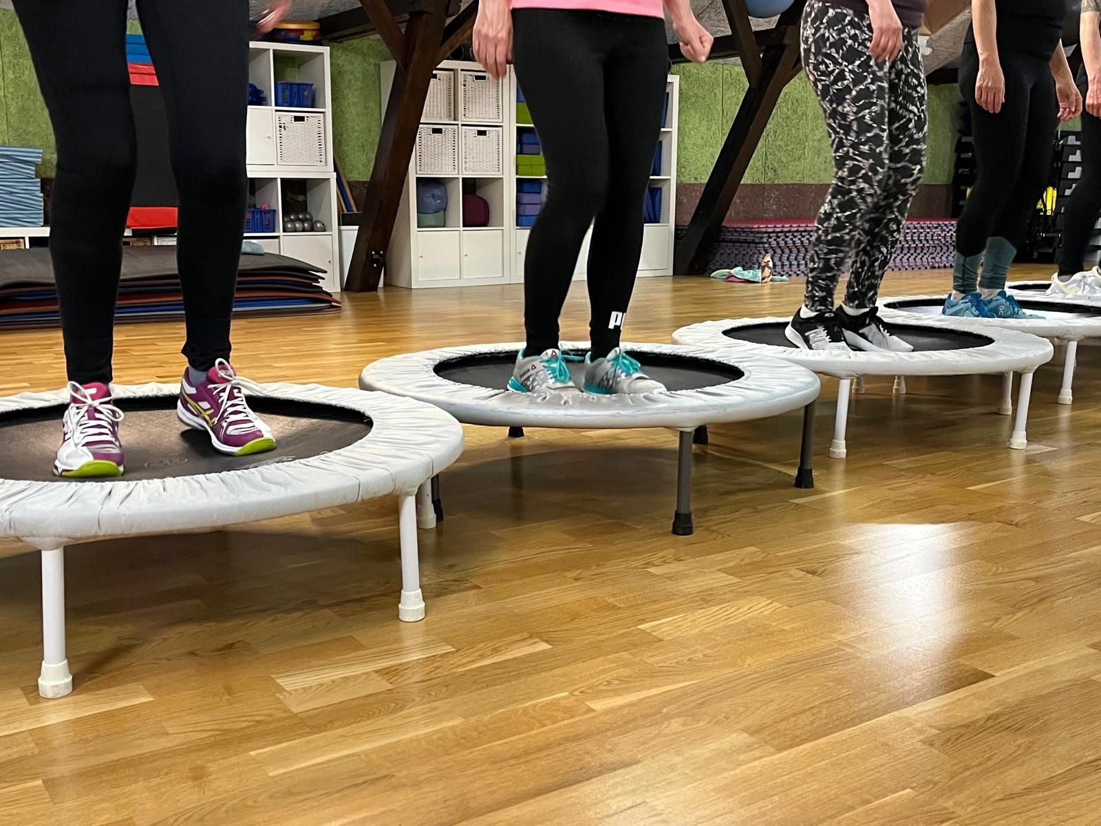 Eine Gruppe von Menschen springt in einer Turnhalle auf Trampolinen.