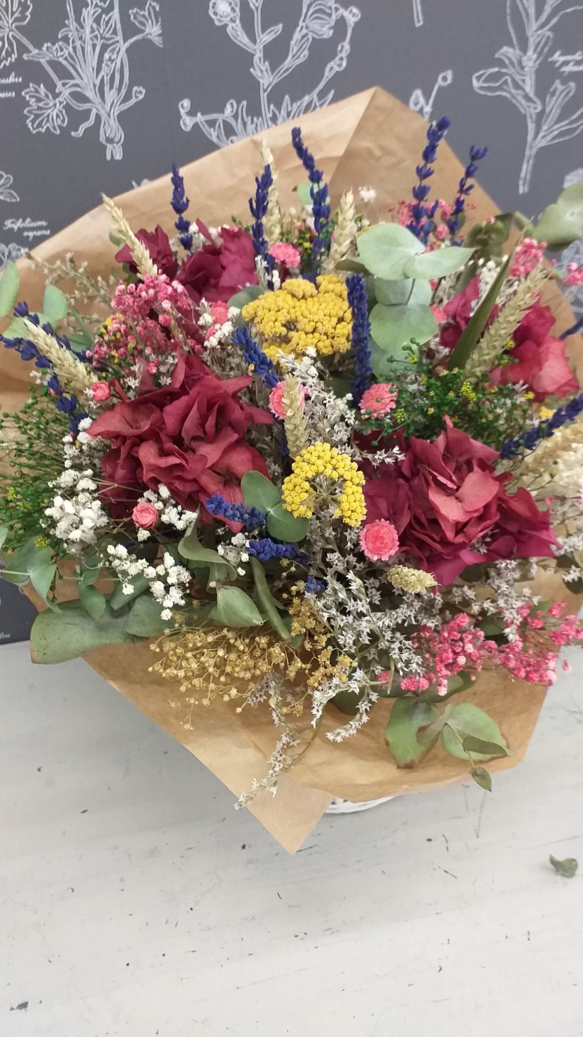 Un ramo de flores envuelto en papel marrón está sobre una mesa.