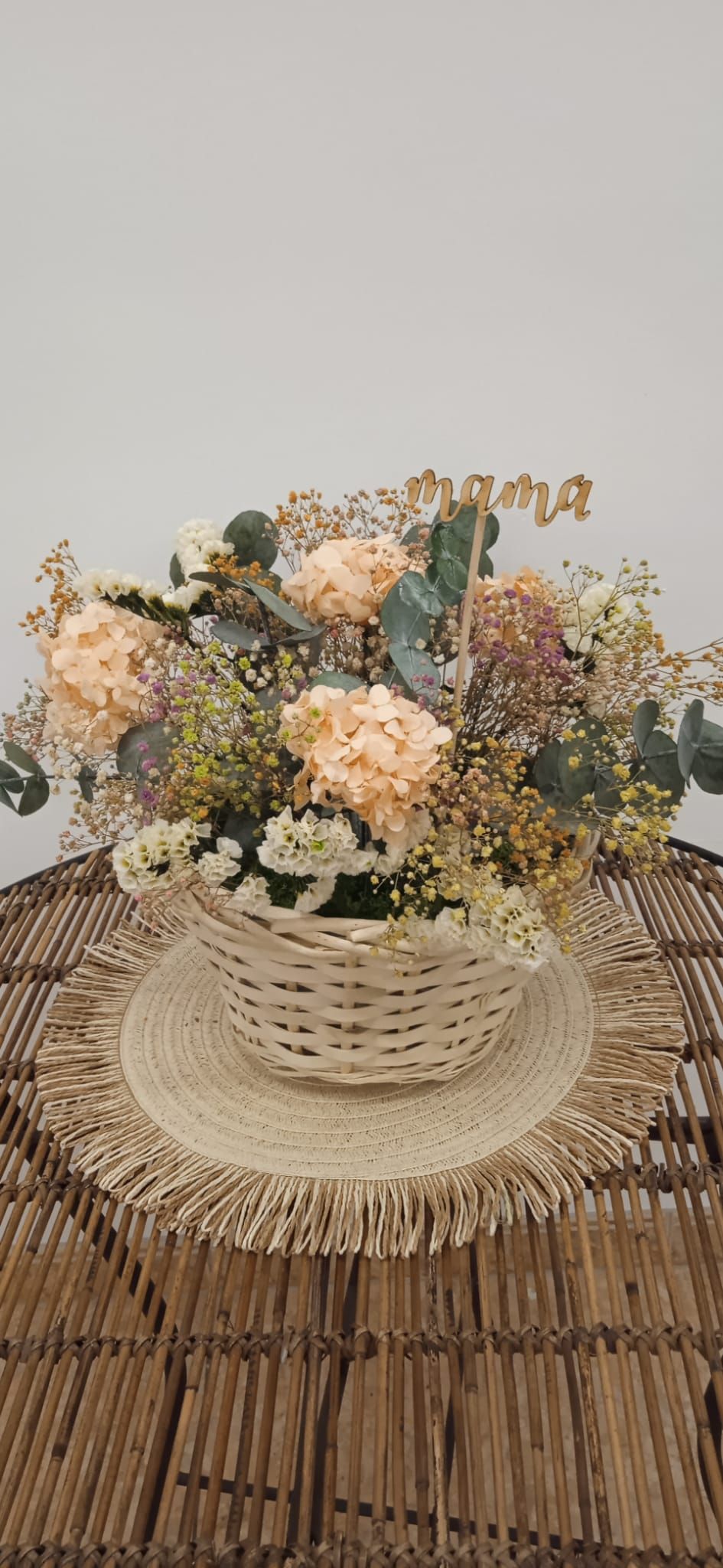 Una cesta llena de flores está sobre una mesa.