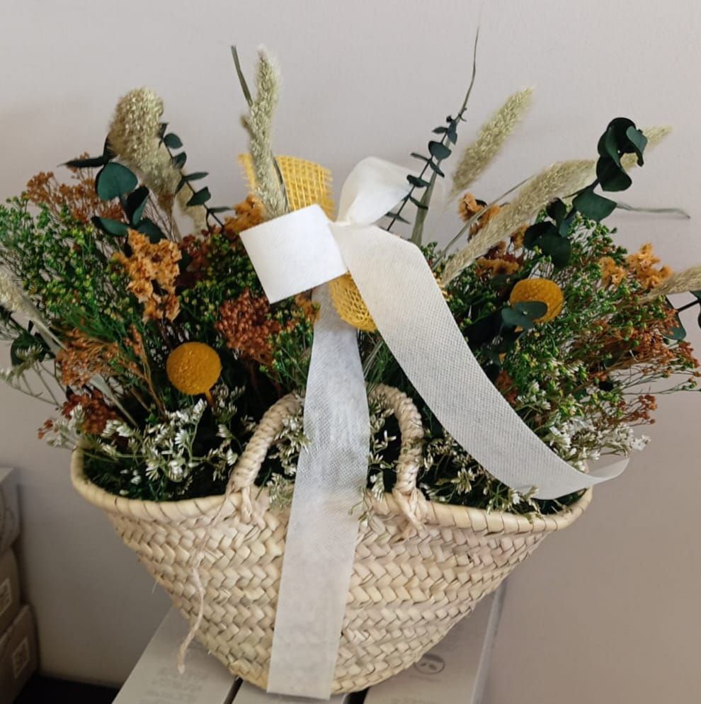 Una cesta de flores con una cinta blanca alrededor.