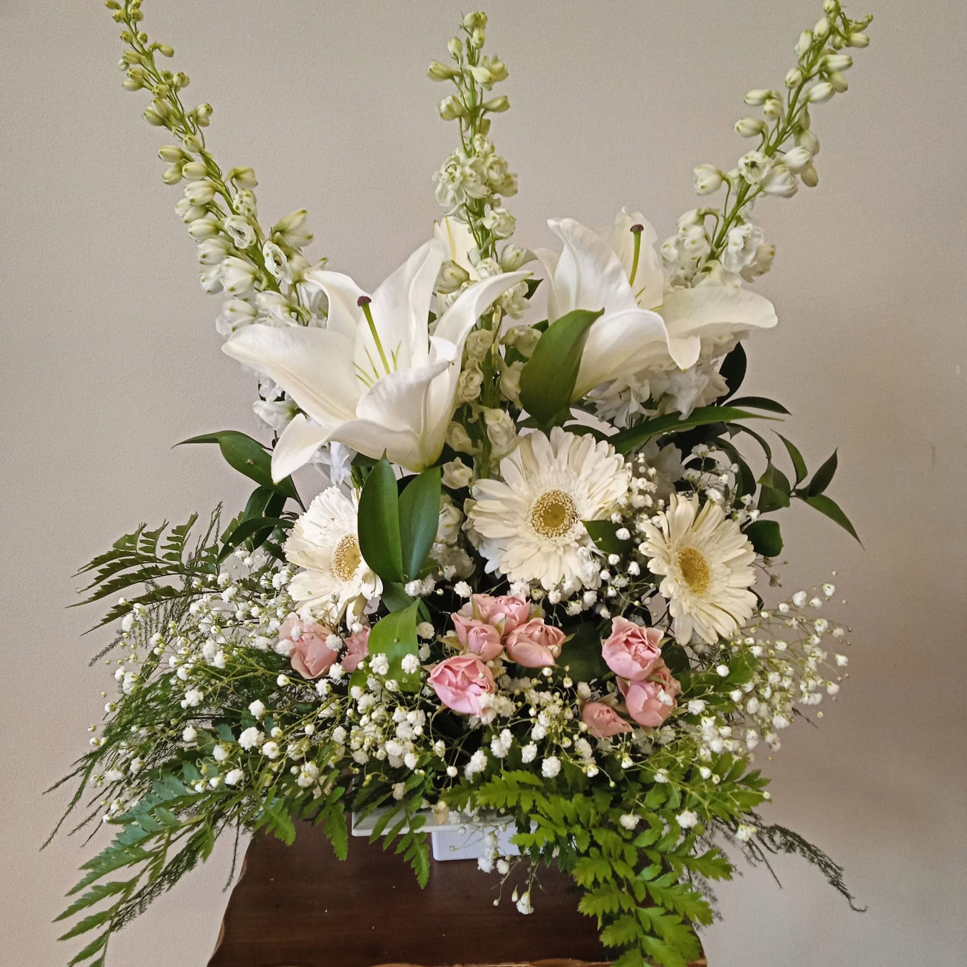 Un jarrón lleno de flores blancas y rosas rosadas