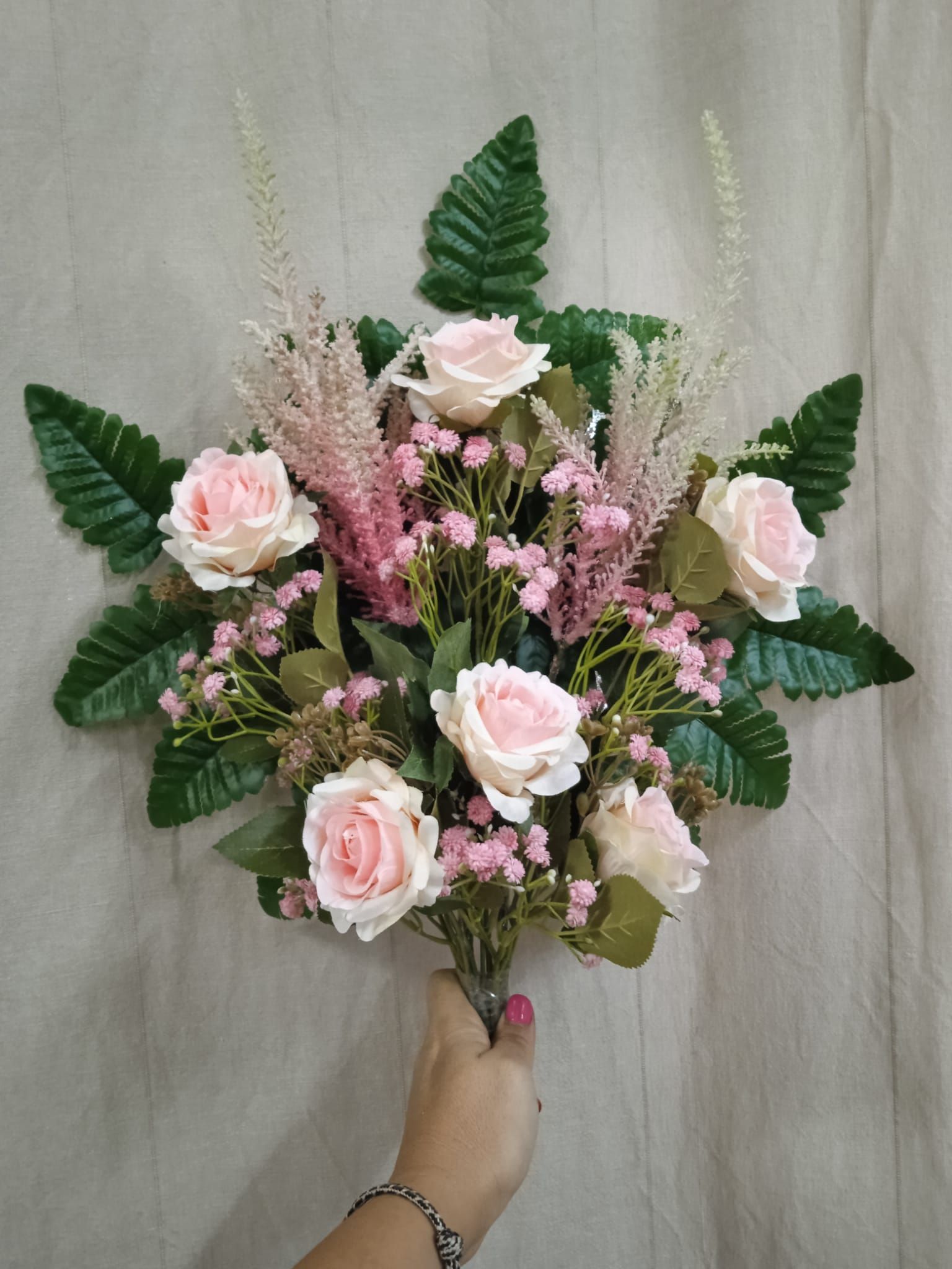 Una persona sostiene un ramo de rosas rosadas y flores de bebé.