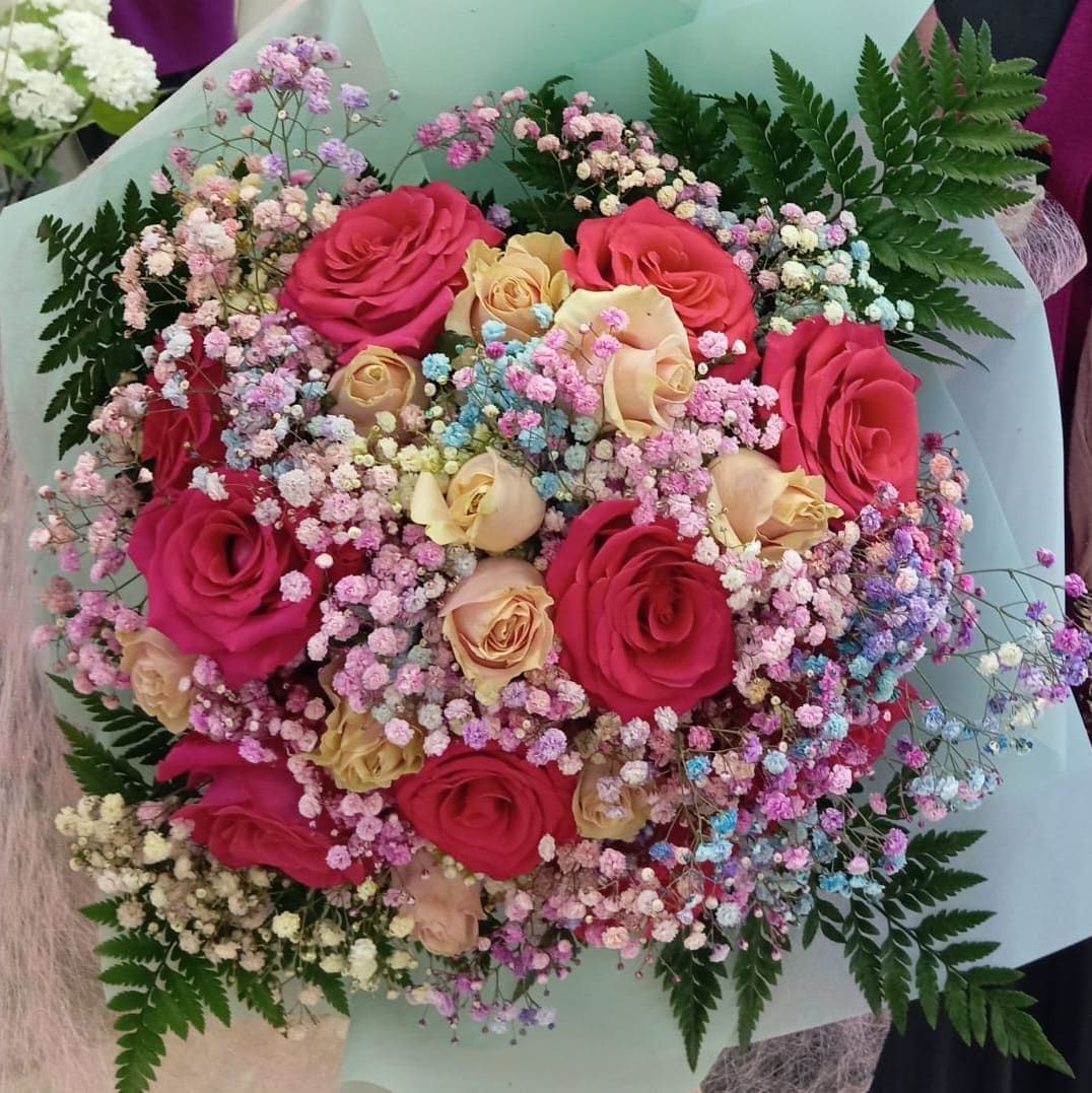 Un ramo de rosas rosadas y amarillas y aliento de bebé.