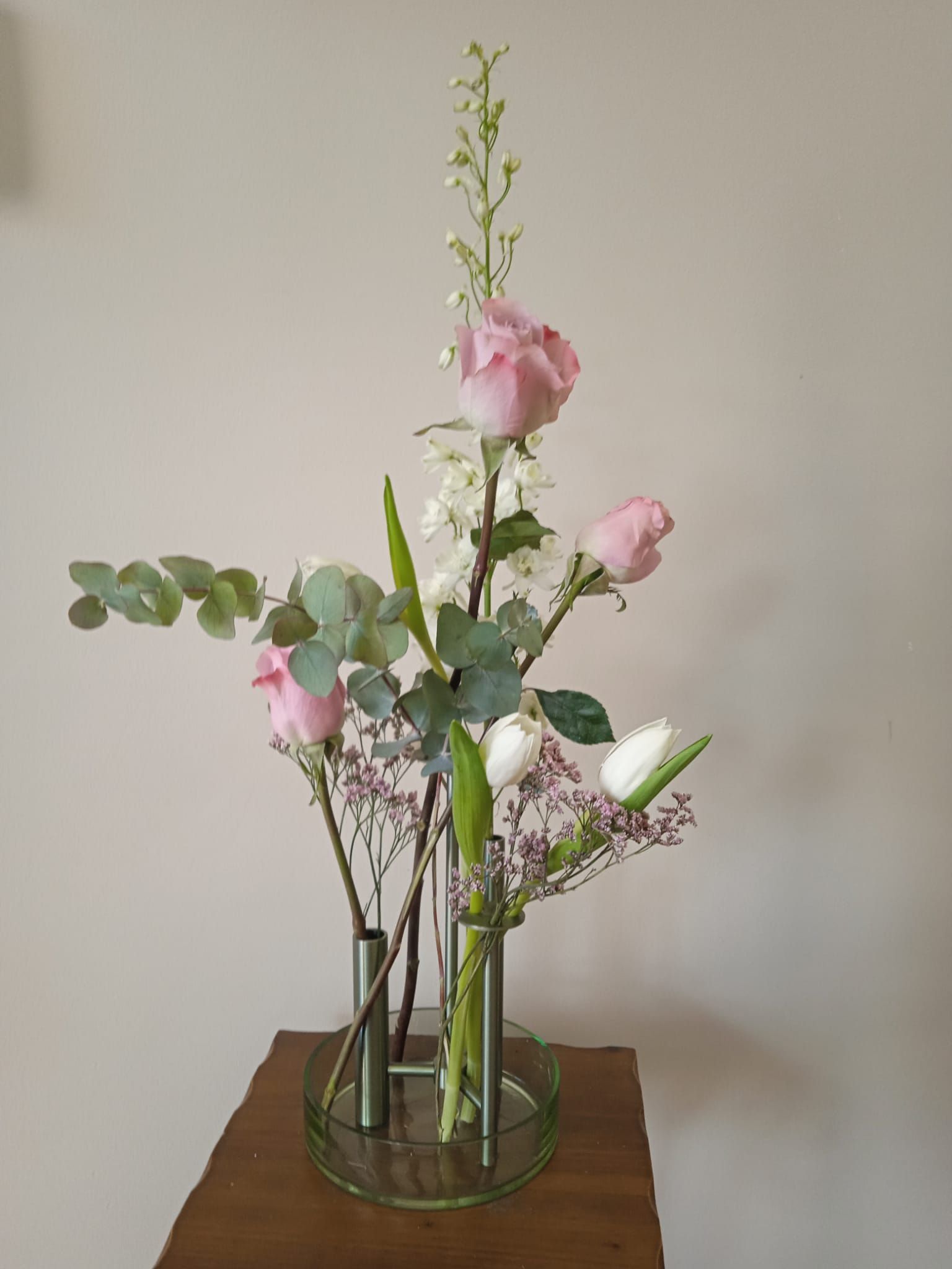 Un jarrón lleno de flores está sobre una mesa de madera.