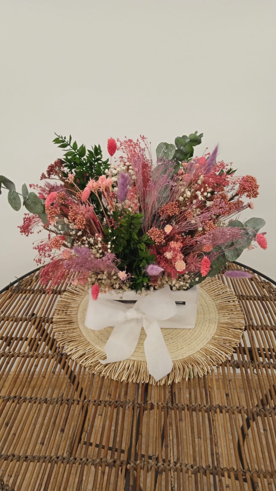 Un ramo de flores secas está sobre una mesa de mimbre.