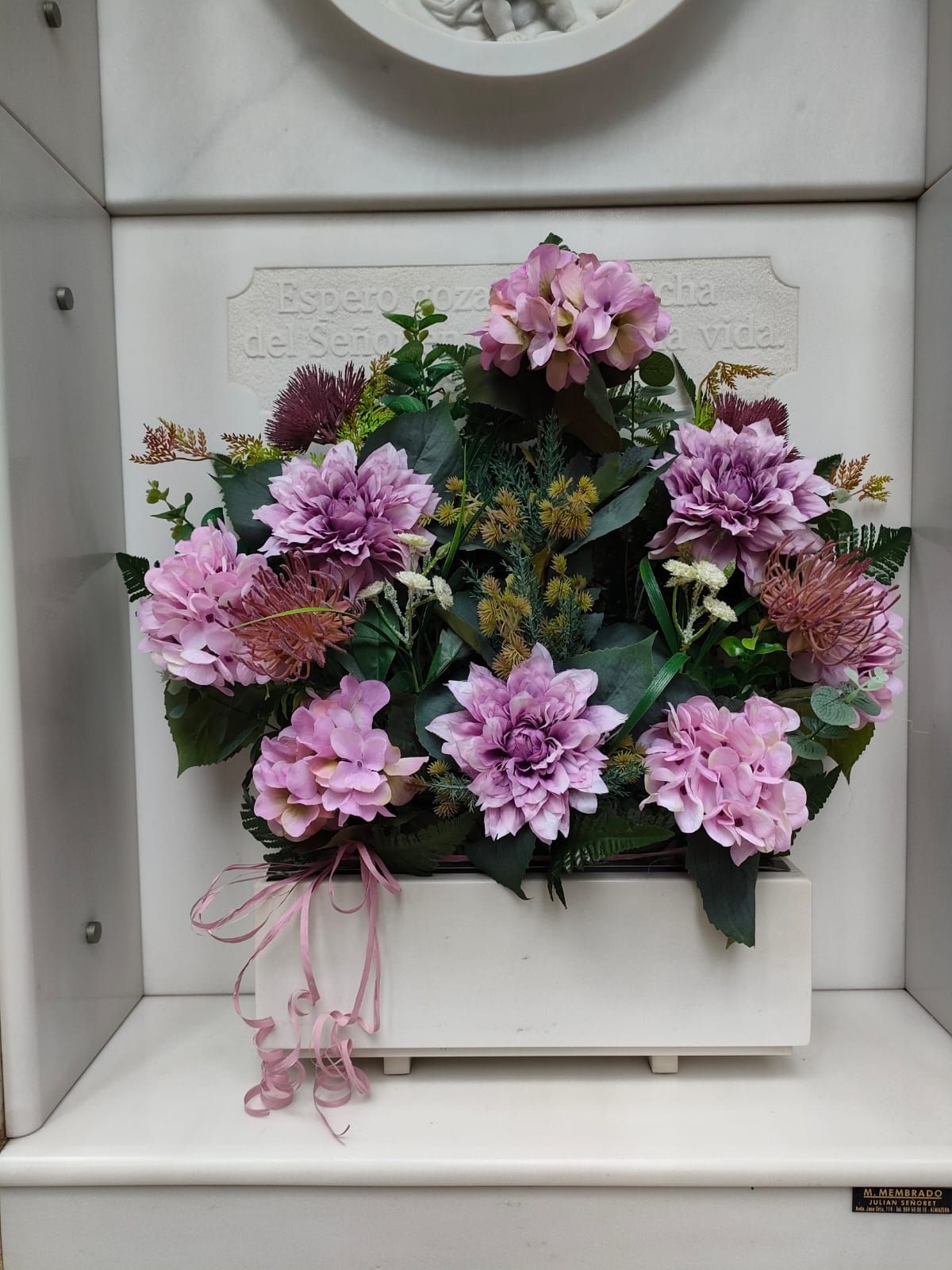 Una caja blanca llena de flores moradas y vegetación.