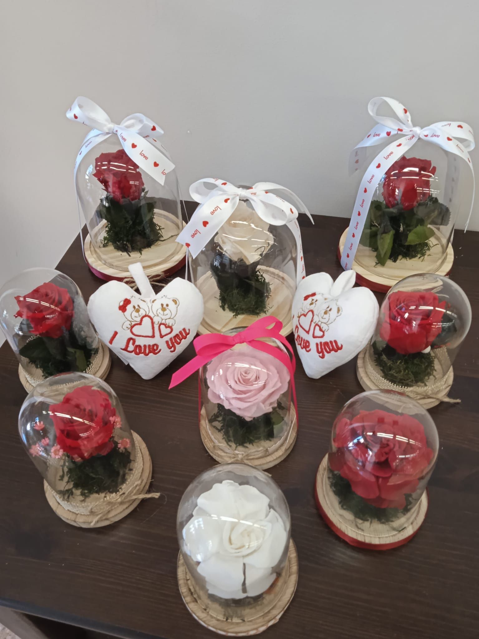 Una mesa cubierta con rosas y corazones en cúpulas de cristal.