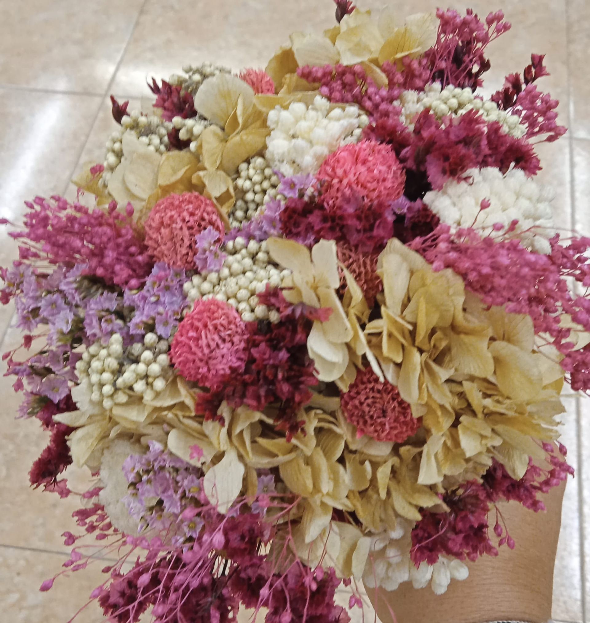 Una persona sostiene un ramo de flores rosas y moradas.
