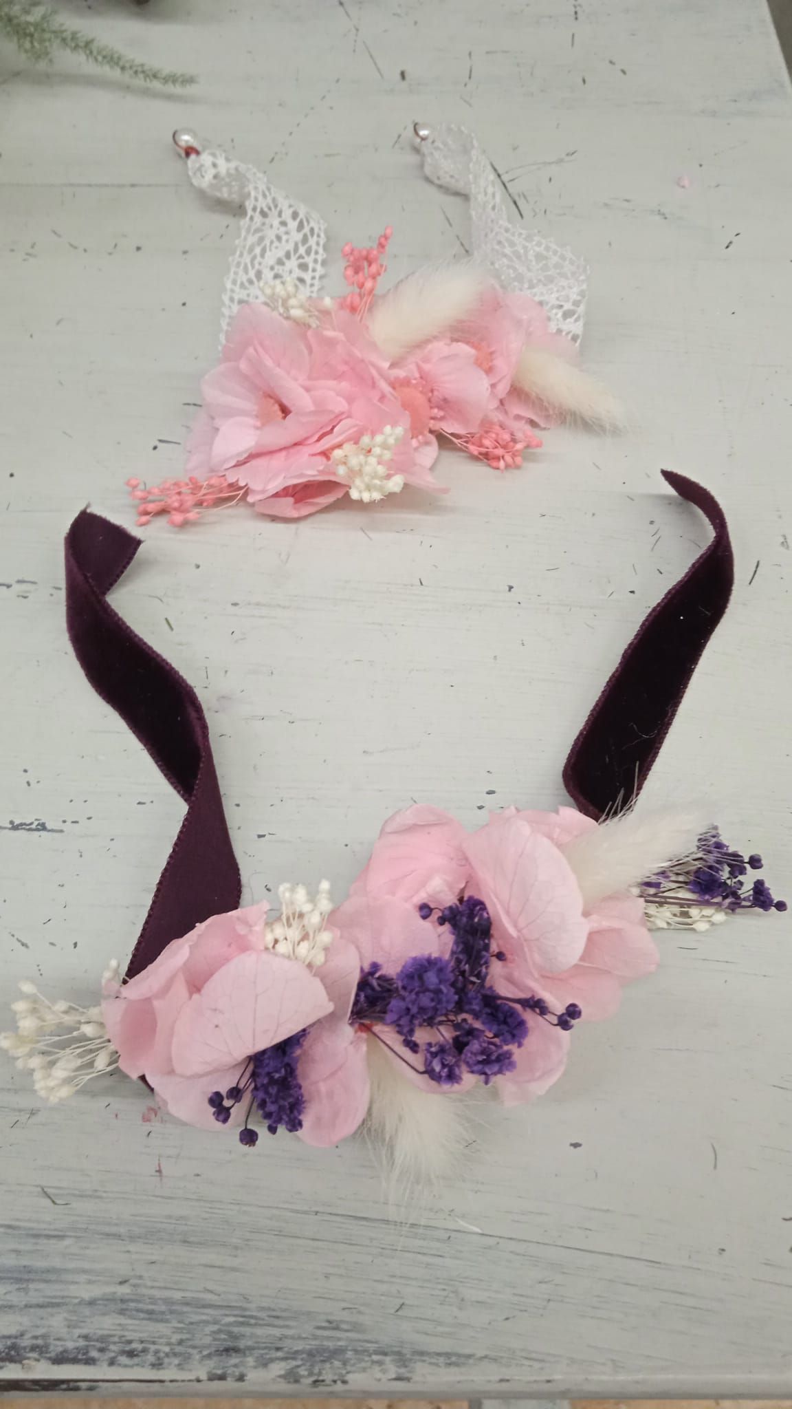 Una diadema con flores rosas y moradas sobre una mesa blanca.