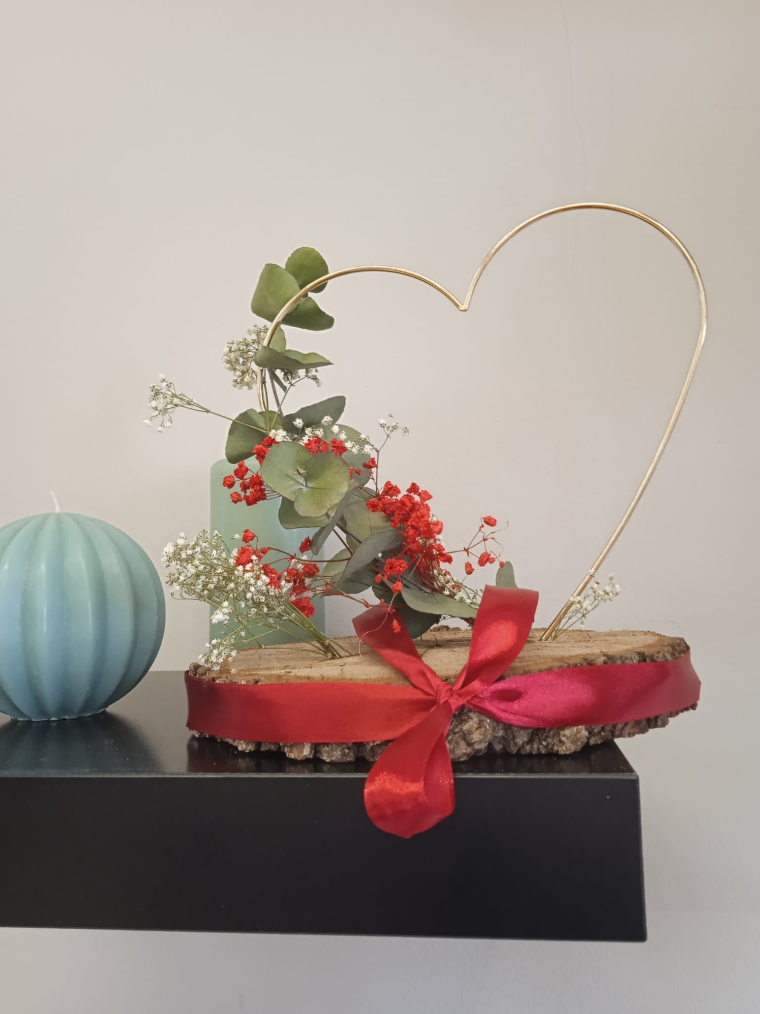 Una decoración en forma de corazón con flores y una vela sobre una mesa.