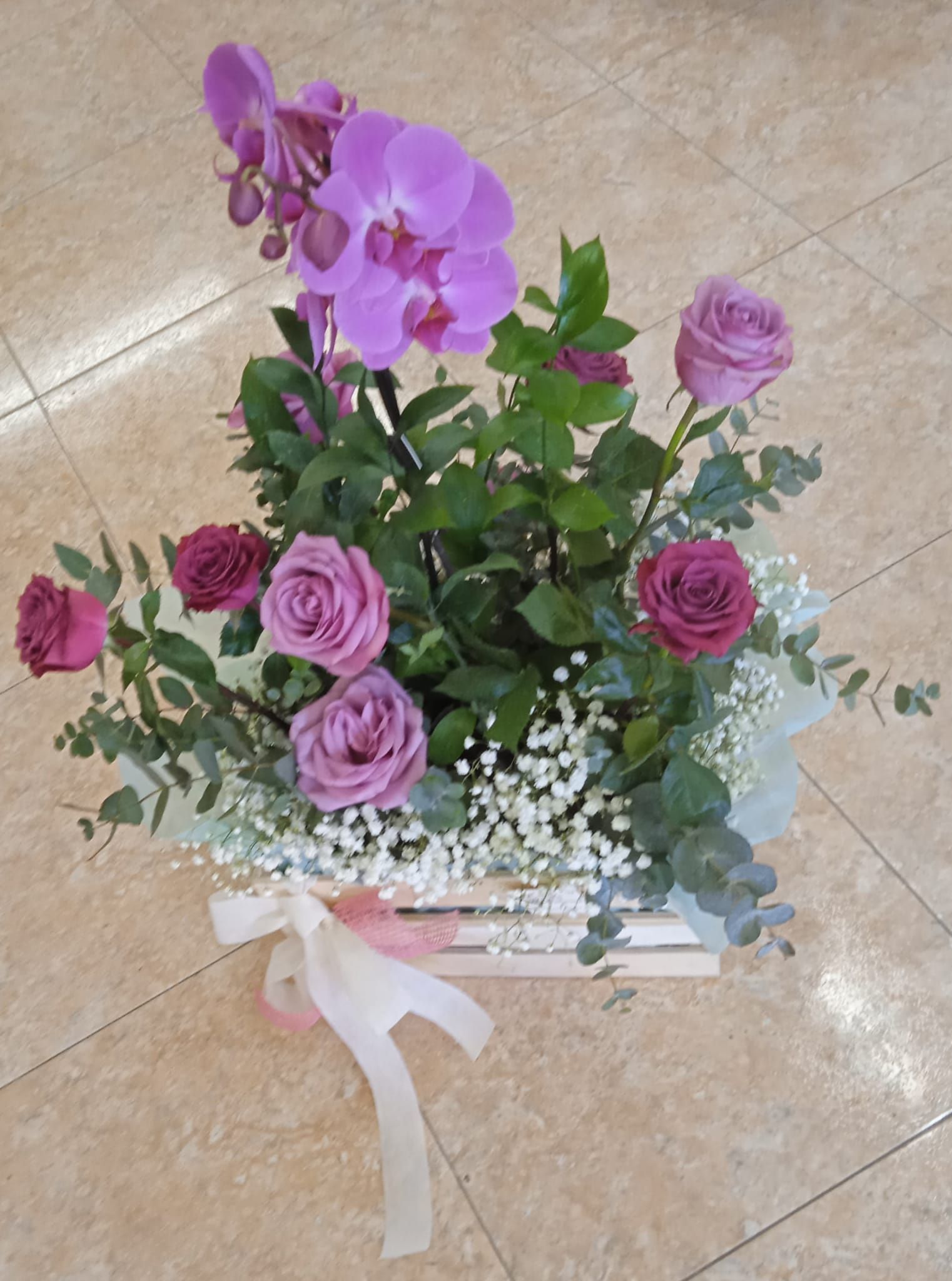 Una caja de madera llena de flores violetas y aliento de bebé.