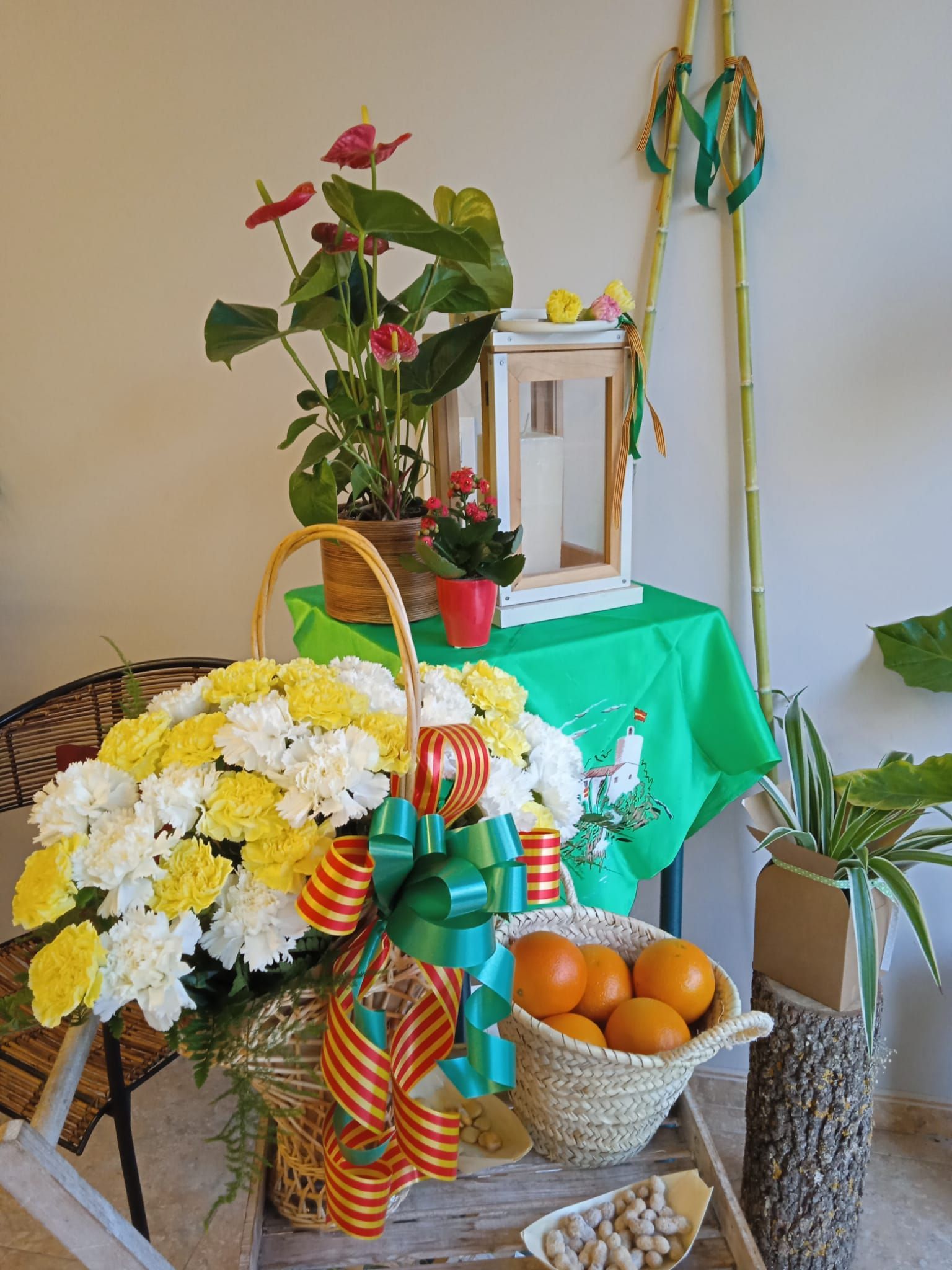 Una mesa con una cesta de flores y naranjas encima.