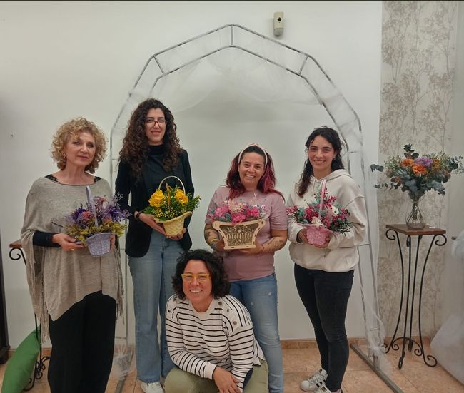 Un grupo de mujeres posan para una fotografía mientras sostienen cestas de flores.