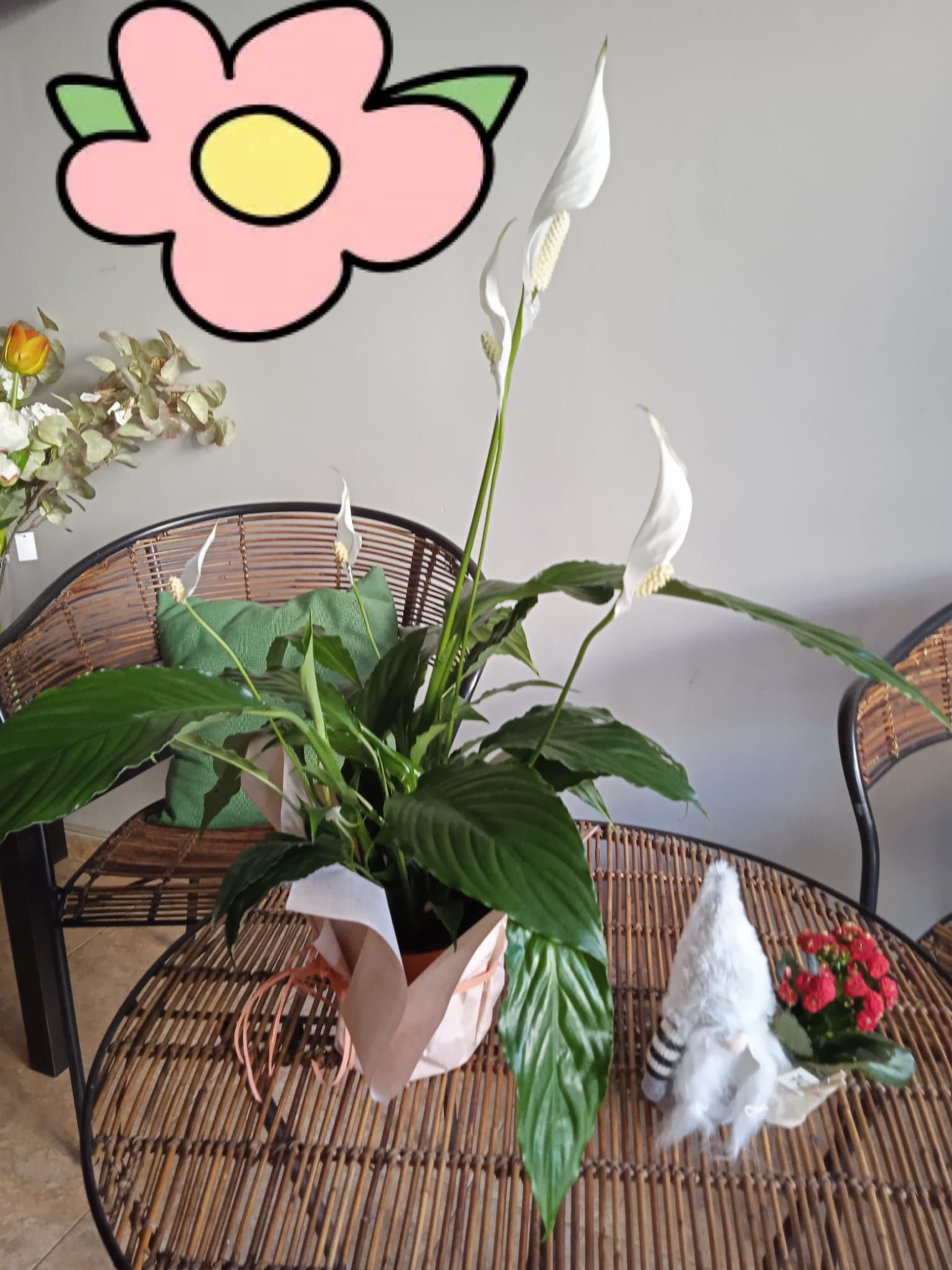 Un dibujo de una flor está encima de una planta en maceta sobre una mesa.