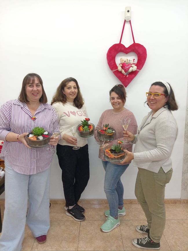 Un grupo de mujeres están de pie una al lado de la otra sosteniendo cuencos de flores.