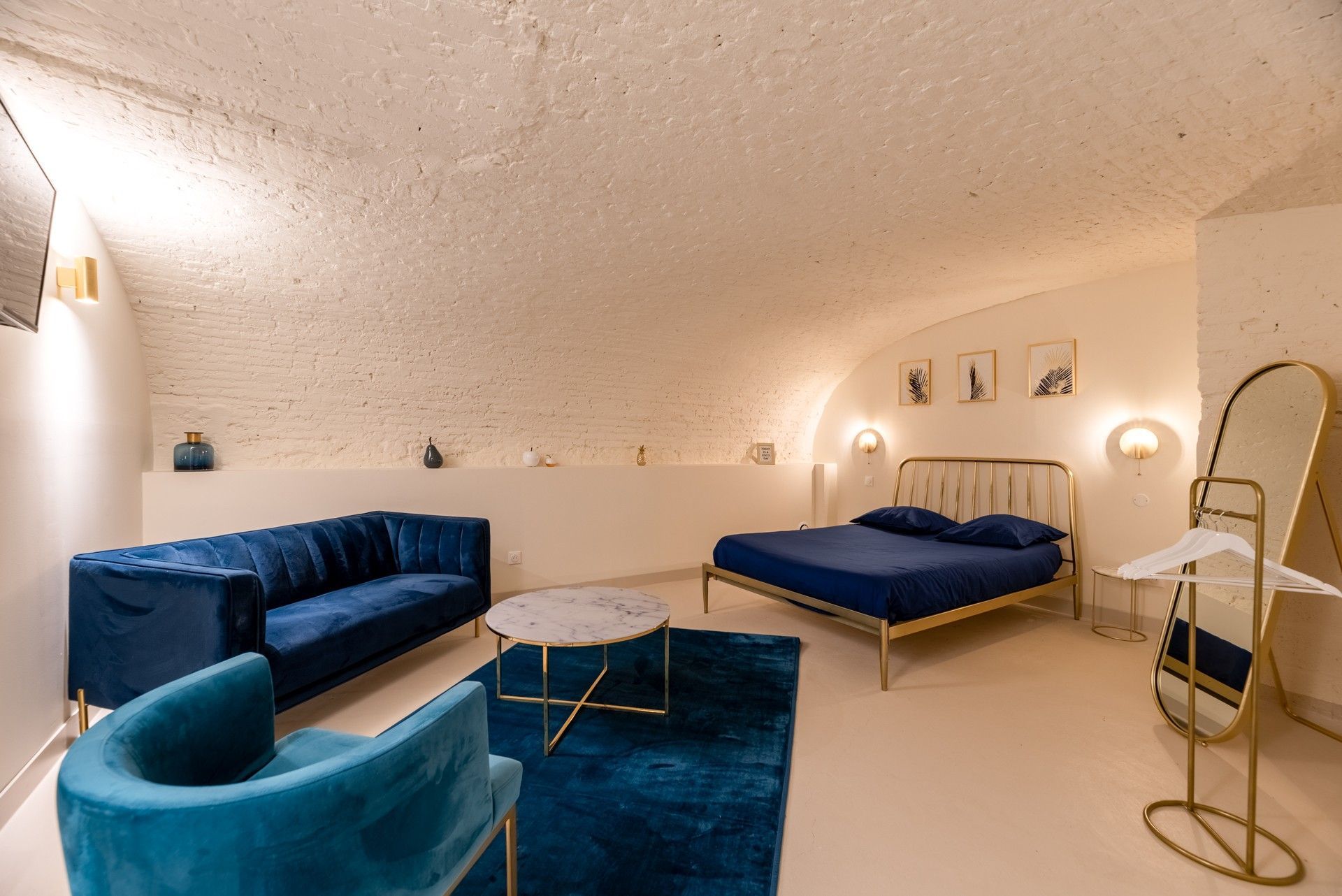 Un lit et deux canapés bleu dans une cave aménagée.