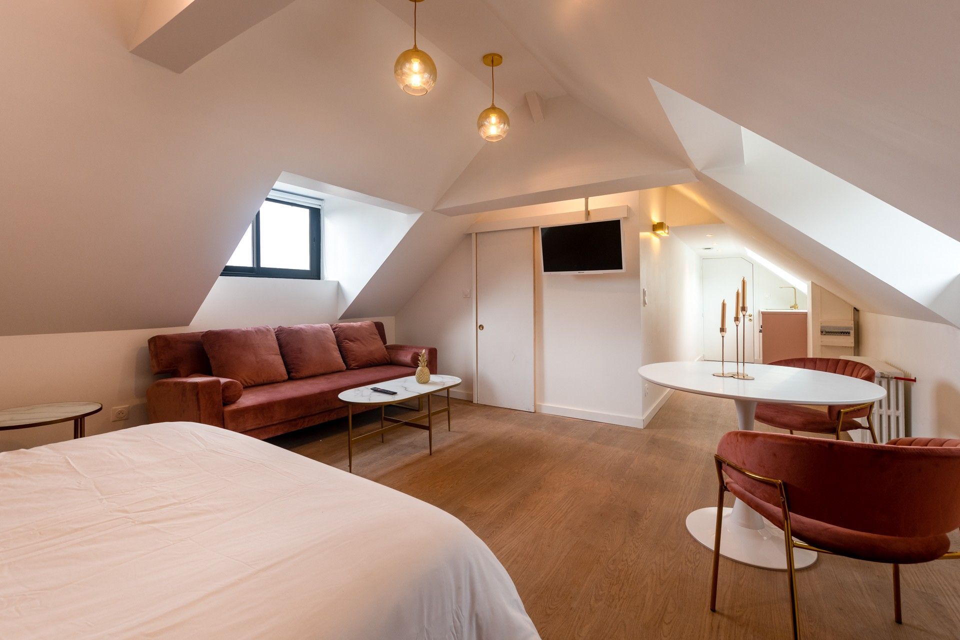 Un lit dans une grande pièce aménagée sous les combles.