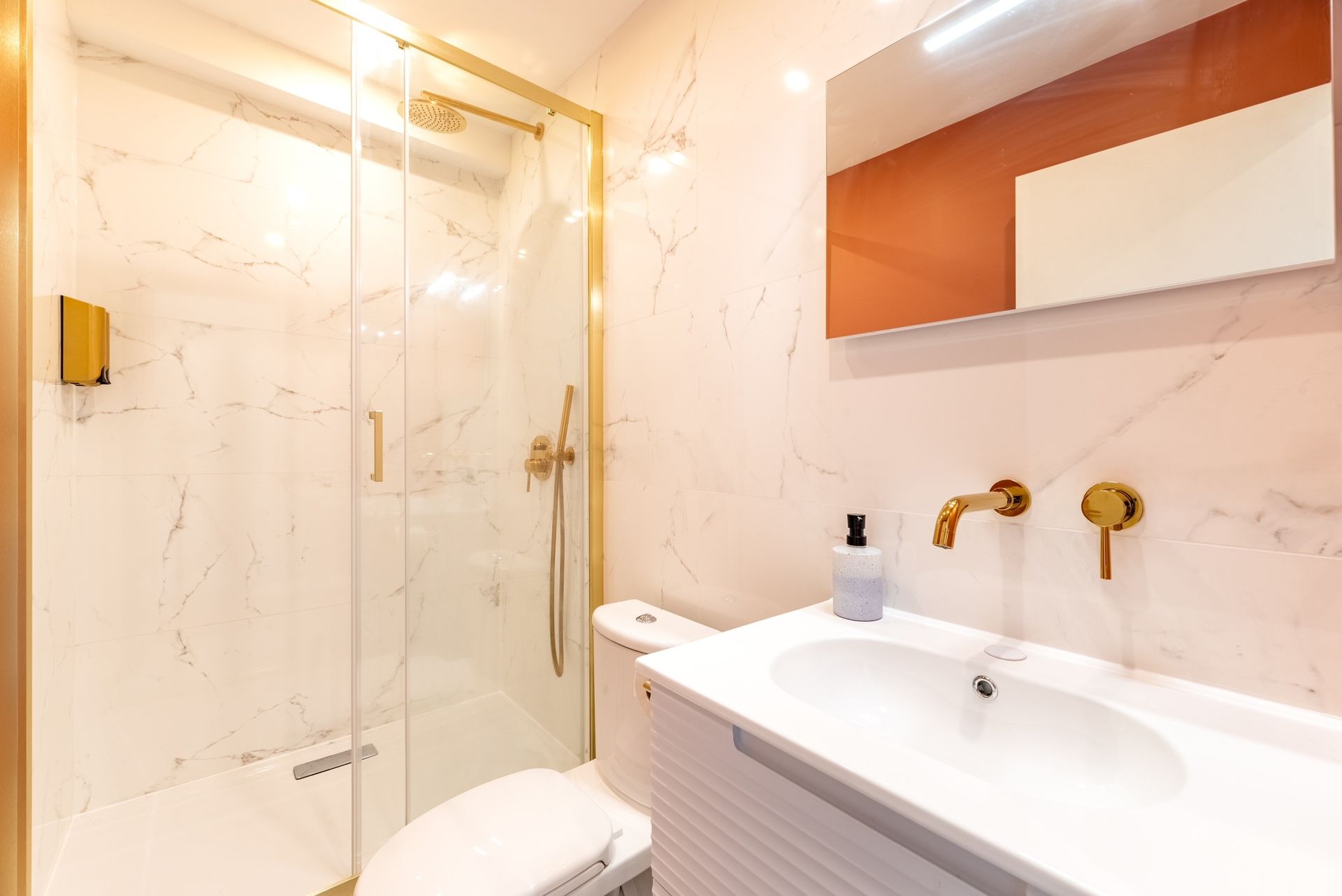 Salle de bains avec douche et vasque entièrement carrelée.
