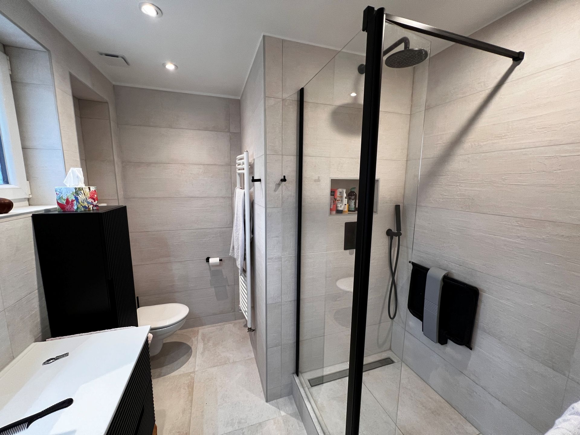 Salle de bains entièrement carrelée avec toilette et cabine de douche 01