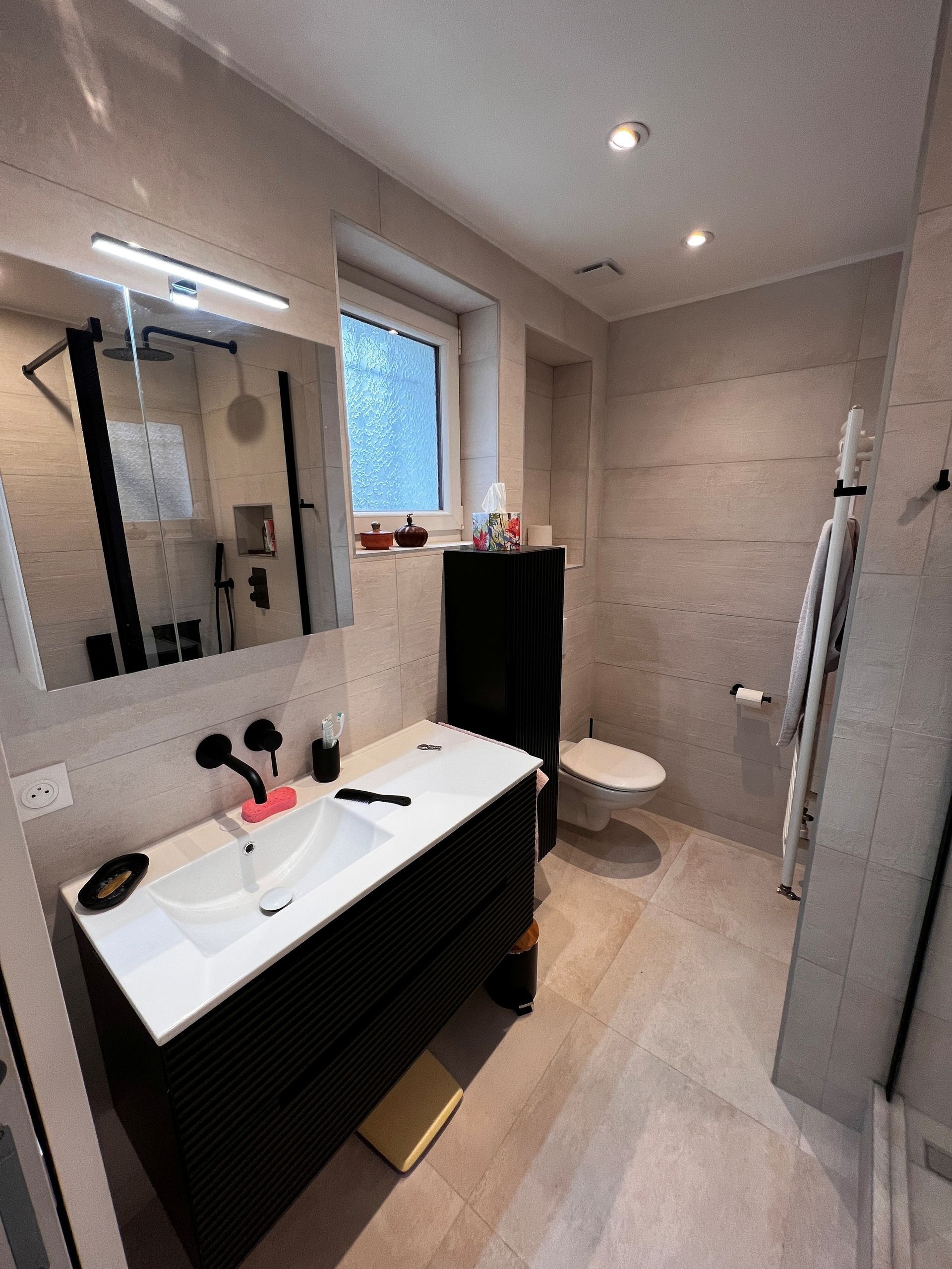 Salle de bains entièrement carrelée avec toilette et cabine de douche 02