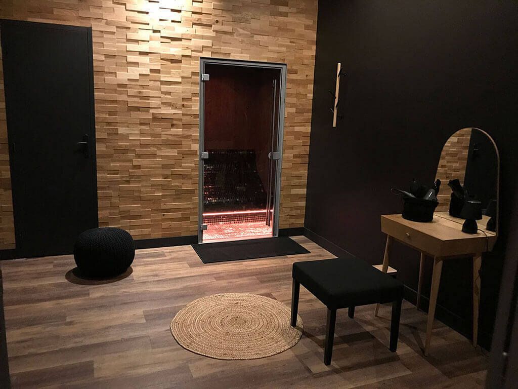 Intérieur d'une pièce noir et brun menant vers la porte d'une douche.