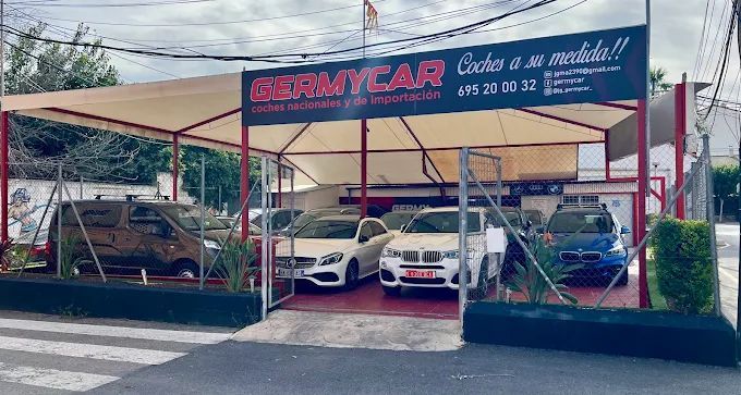 Coches en venta en el concesionario GERMYCAR bajo un toldo rojo y tostado.