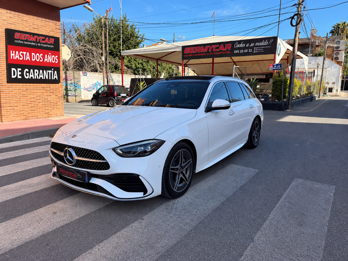 Un Volvo XC40 negro estacionado en un paso de peatones frente a un concesionario de automóviles en un día soleado.