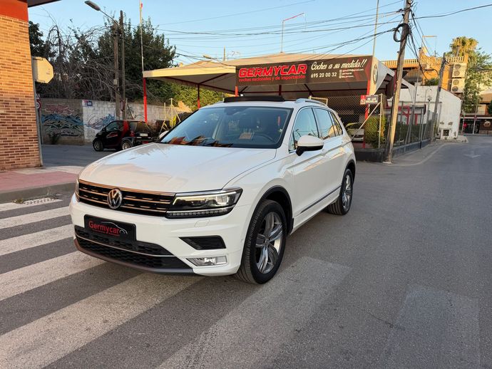 SUV Volkswagen Tiguan negro estacionado en un cruce peatonal frente a un concesionario de automóviles.