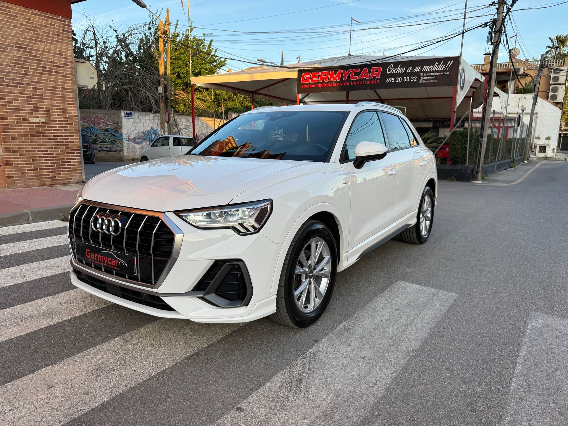 SUV Volkswagen Tiguan negro estacionado en un cruce peatonal frente a un concesionario de automóviles.