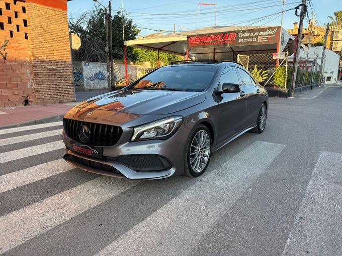 Un Volvo XC40 negro estacionado en un paso de peatones frente a un concesionario de automóviles en un día soleado.