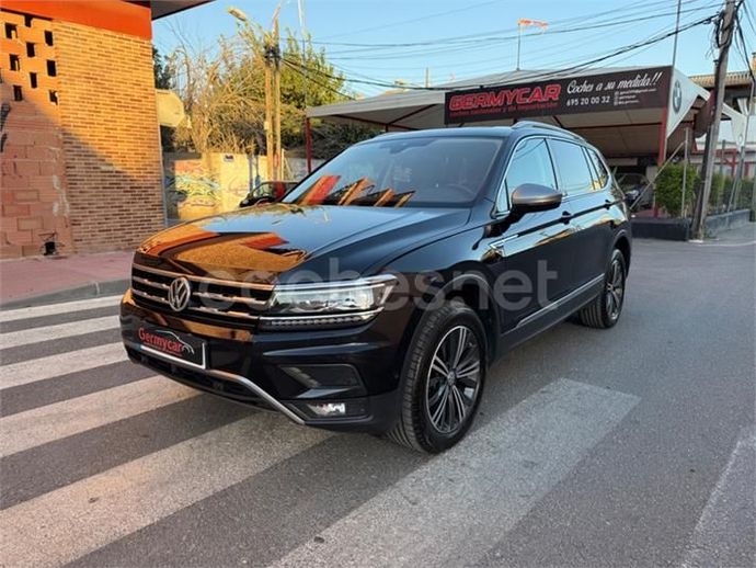 SUV Volkswagen Tiguan negro estacionado en un cruce peatonal frente a un concesionario de automóviles.