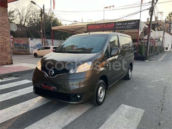 Furgoneta Nissan de color marrón estacionada en un paso de peatones frente a un negocio de alquiler de coches.