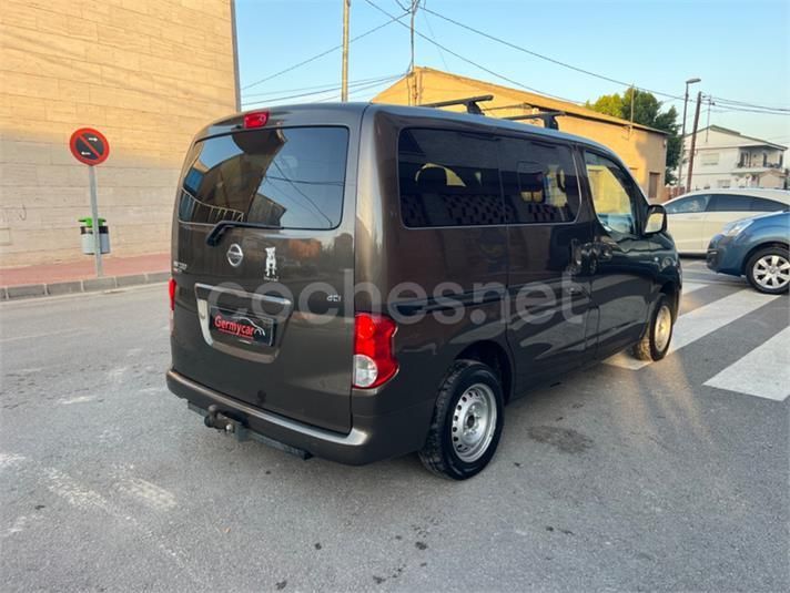 Furgoneta Nissan de color marrón oscuro estacionada en una calle con paso de peatones y edificios.