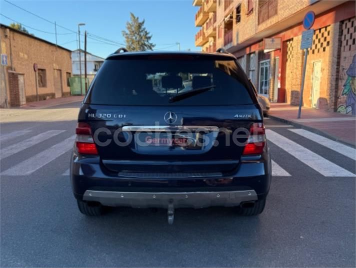 Vista trasera de un Mercedes ML 320 CDI azul oscuro estacionado en una calle con edificios.