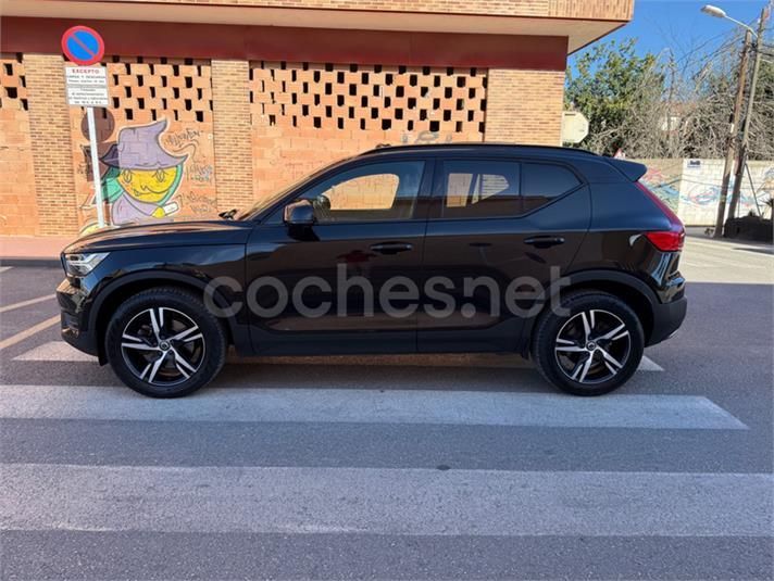 Volvo XC40 negro estacionado en un paso de peatones frente a un edificio de ladrillos.