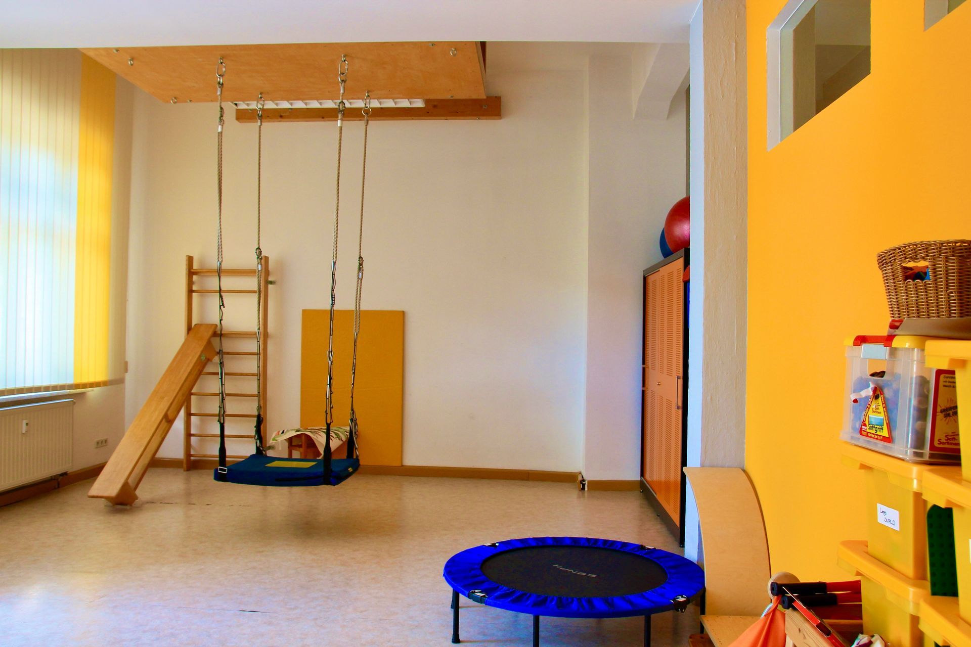 Ein Aktivitätsraum mit kleinem Trampolin, Schaukel und Klettermöglichkeiten