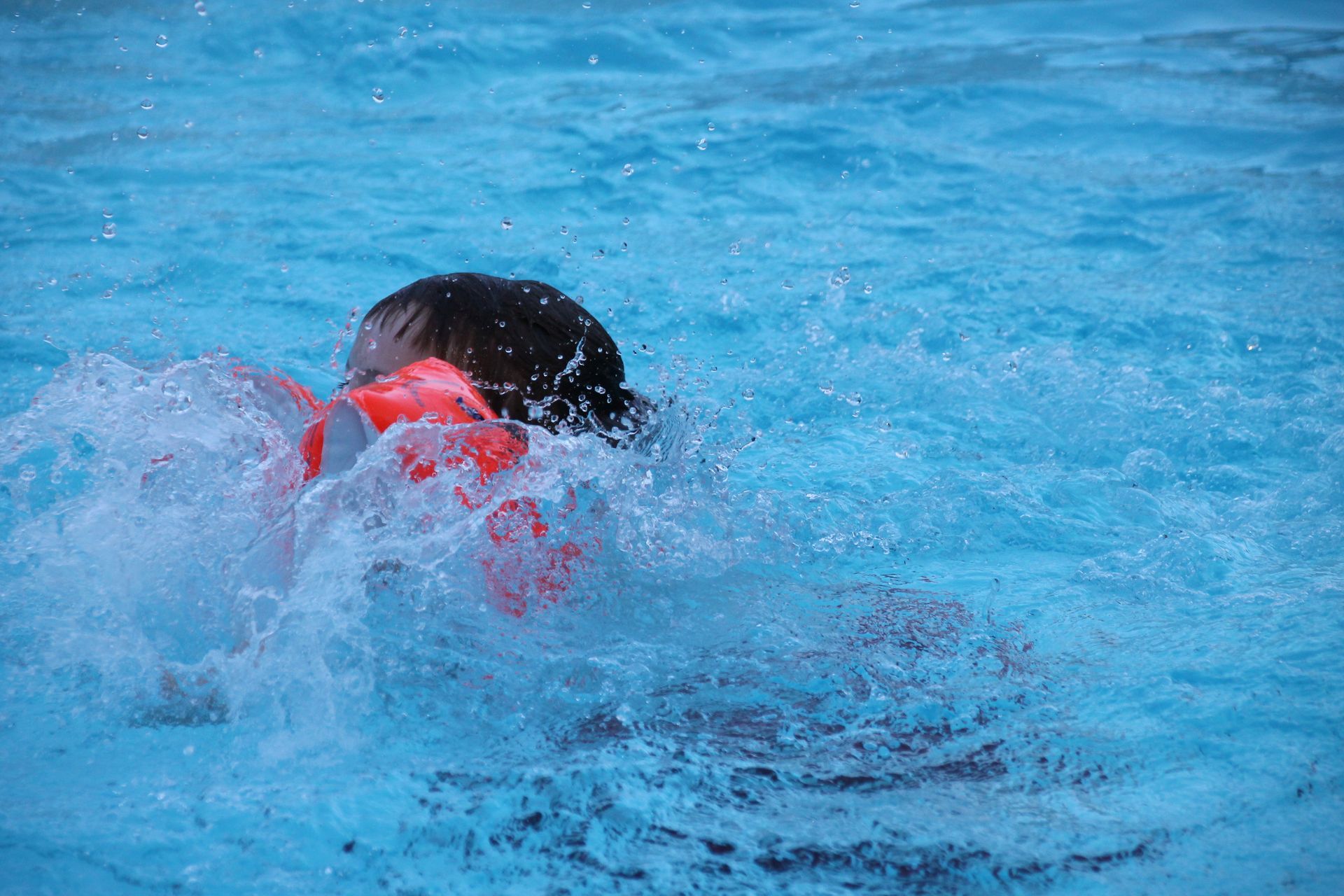 Ein Kind mit Schwimmflügeln ist am schwimmen