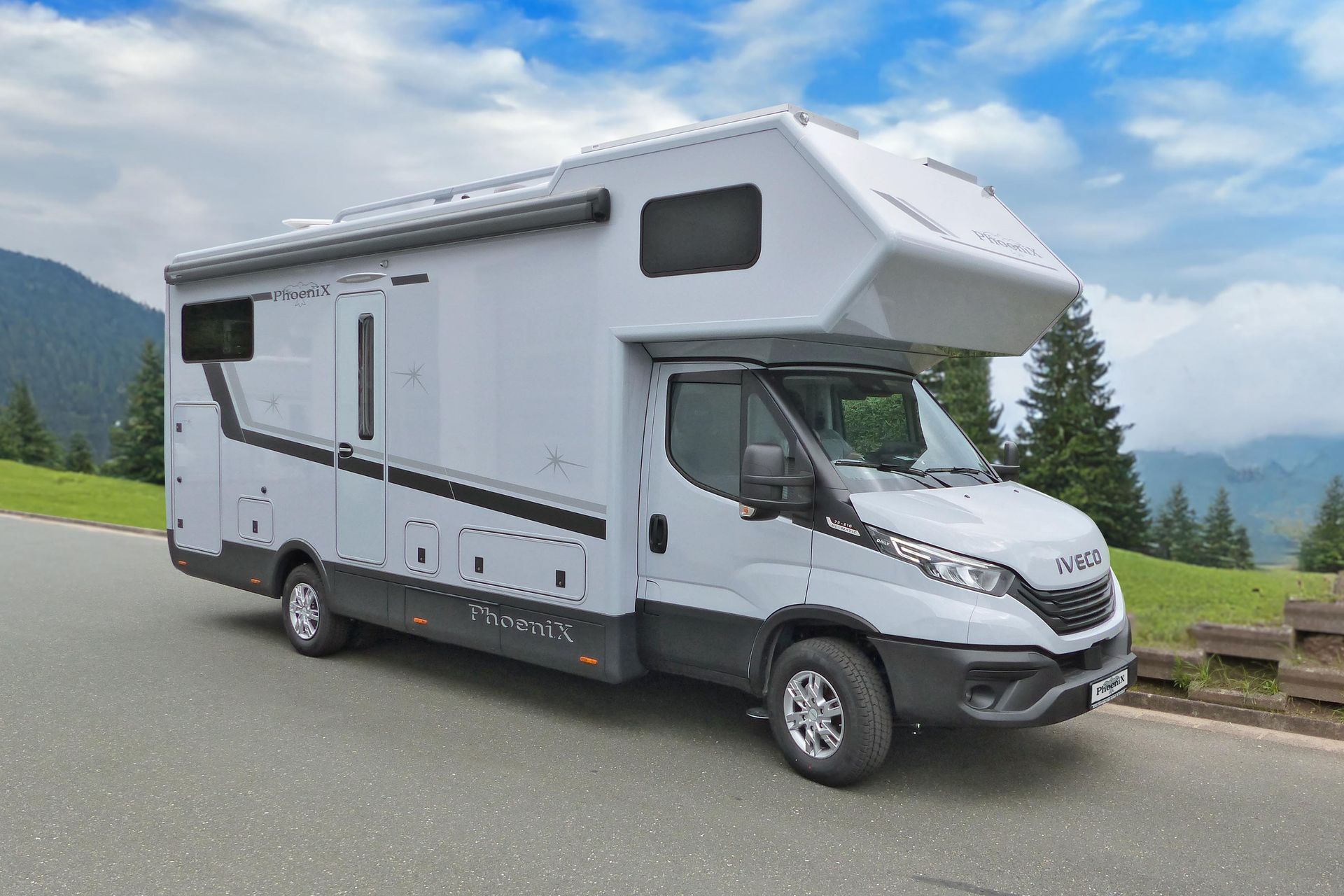 Graues Wohnmobil auf der Straße geparkt, Berge und Bäume im Hintergrund.