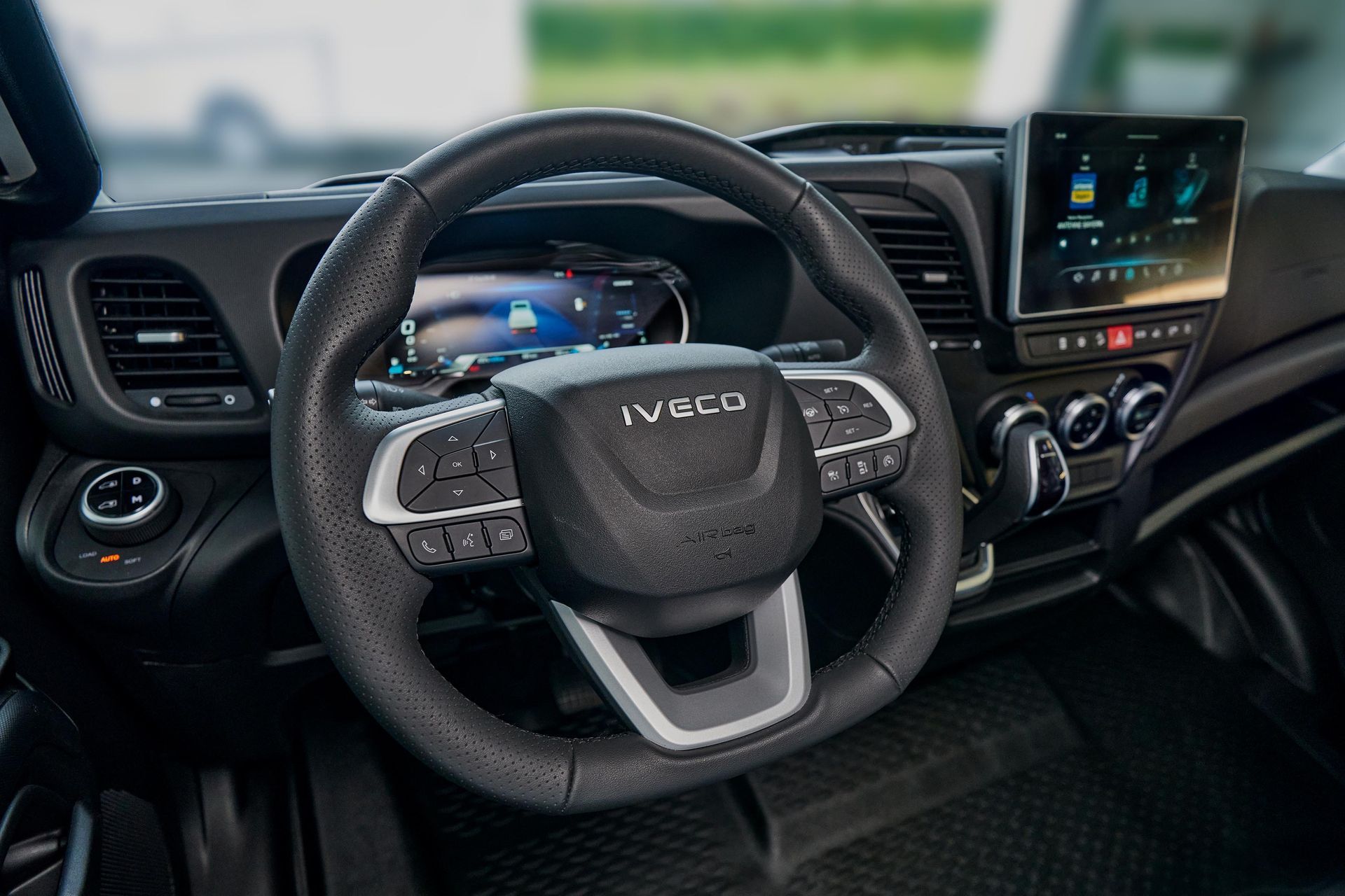 Innenansicht eines IVECO-Lkw mit Fokus auf dem schwarzen Lenkrad, Armaturenbrett und Infotainment-Bildschirm.