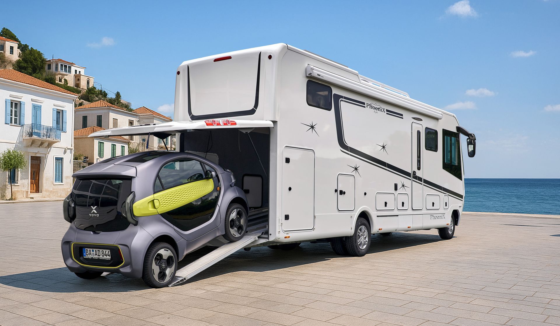 Großes weißes Wohnmobil mit einem kleinen grauen Auto, das auf eine Rampe geladen wird. Strandkulisse.