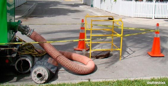 Cônes de sécurité orange et barrière jaune autour d'un gros tuyau sur une zone de travaux routiers