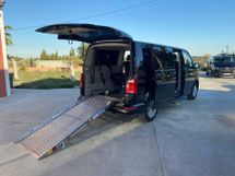 Una camioneta negra con una rampa en la parte trasera está estacionada en un estacionamiento.