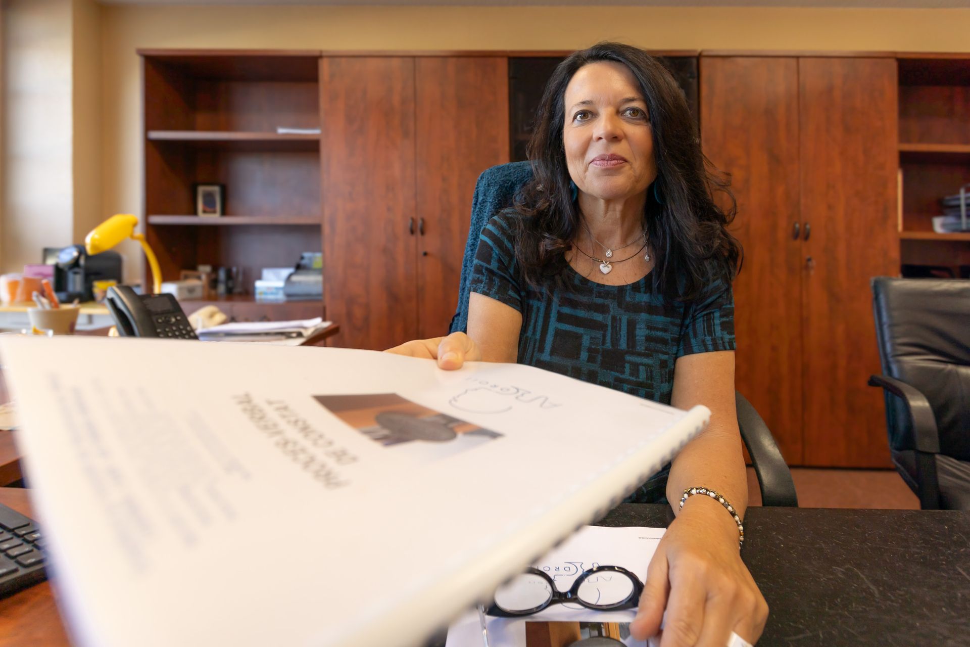 Me Allia ABBASSI assise à son bureau signant un document.