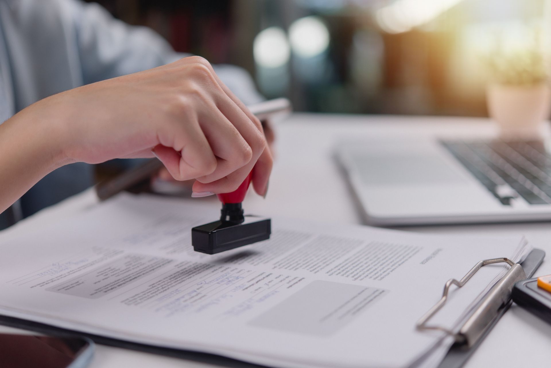 La main d'une femme apposant un tampon officiel sur des documents.