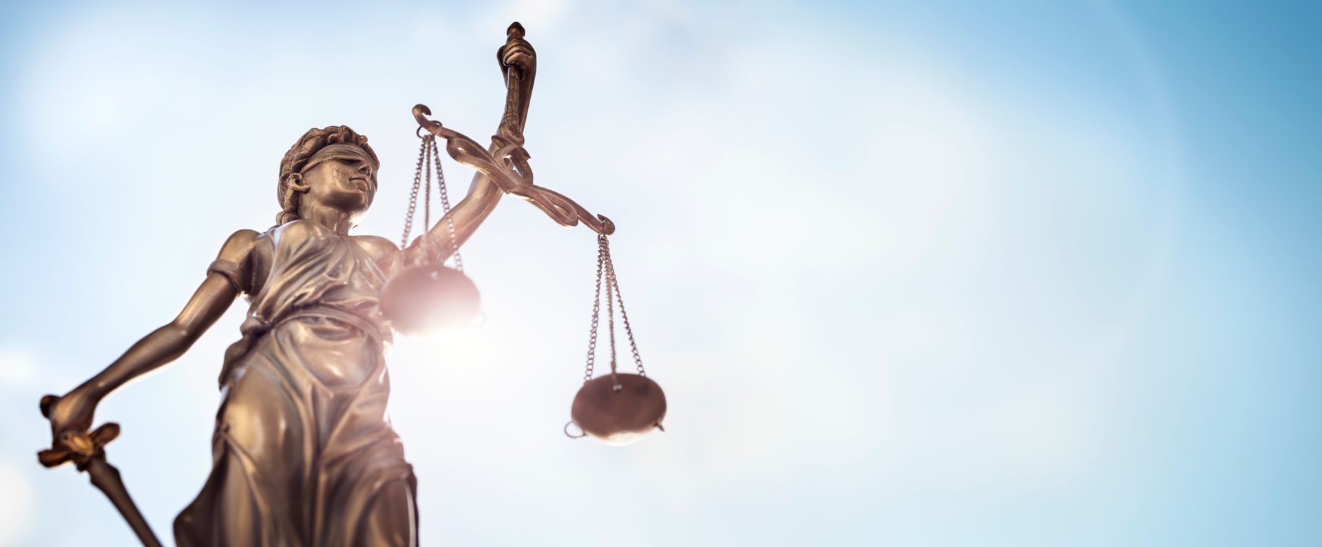 Une statue de la balance de la Justice vue en contreplongée à contrejour.