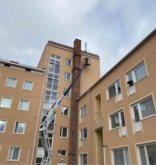 Moderni valkoinen talo mustilla yksityiskohdilla ja puisella terassilla, sininen taivas yläpuolella.