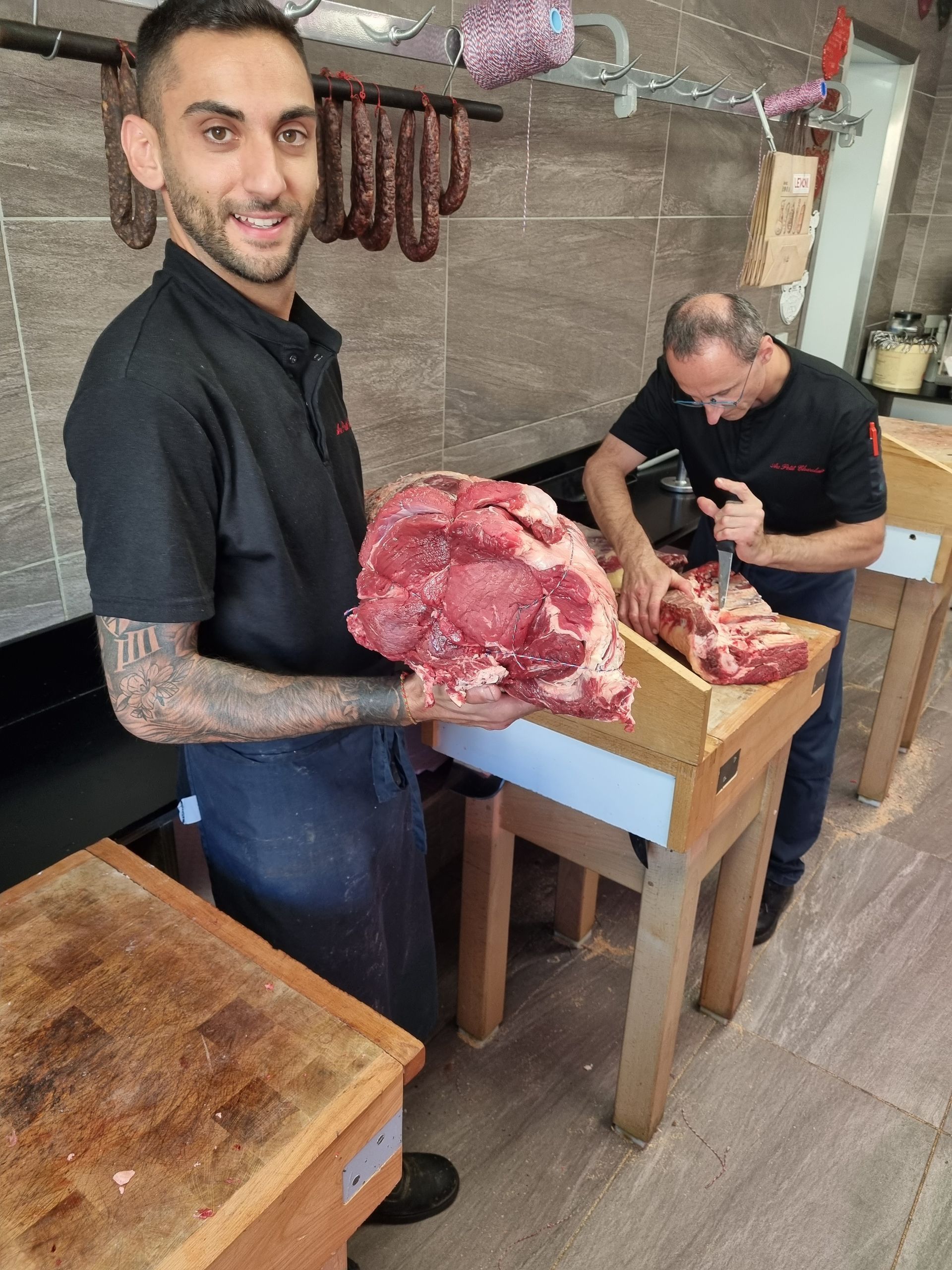 Photo de deux hommes en train de couper un morceau de viande